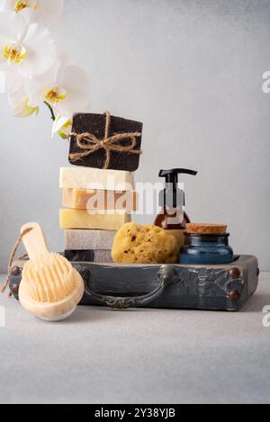 Un set da bagno splendidamente arredato con saponi fatti a mano, una spazzola posteriore in legno e una spugna naturale. Ideale per la cura della pelle naturale e per le routine di benessere Foto Stock