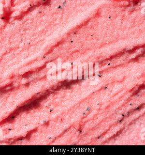 Consistenza scrub rosa o rosso con zucchero o sale. Scrub rosa - prodotto per la cura della pelle con estratto di frutta come sfondo cosmetico. Foto Stock