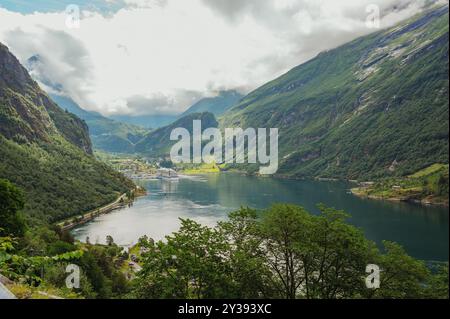 Nave da crociera nel fiordo di Geiranger circondata da rigogliose e ripide montagne Foto Stock