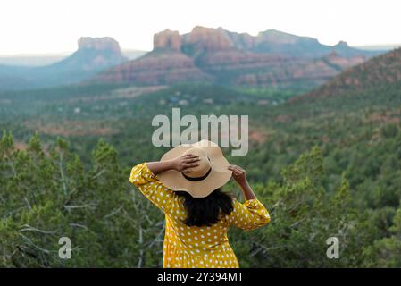 Donna con un abito a pois giallo che si affaccia sulle rocce rosse di Sedona Foto Stock