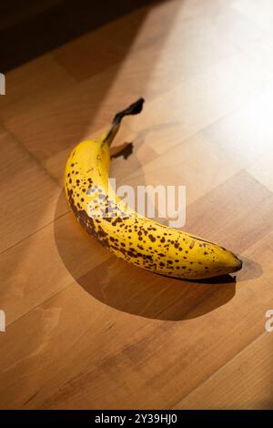 Banana singola strappata su sfondo in legno, vista dall'alto, foto ravvicinata, nessuno. Foto Stock