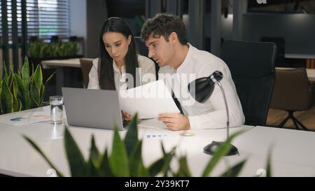 Donna e uomo caucasico che lavorano insieme con documenti e computer portatile lavoro di ufficio colleghi uomini d'affari e donne Foto Stock