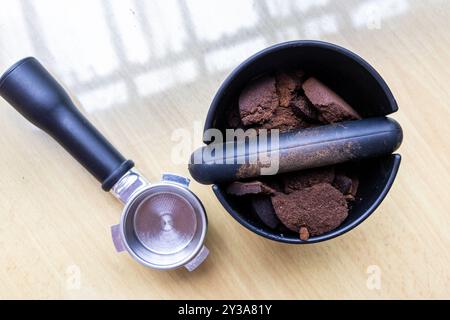 Caffè compattato macinato in scatola con portafiltro accanto. I fondi di caffè sono eccellenti fertilizzanti naturali e organici. Foto Stock