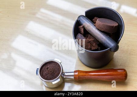 Caffè compattato macinato in scatola con portafiltro accanto. I fondi di caffè sono eccellenti fertilizzanti naturali e organici. Foto Stock
