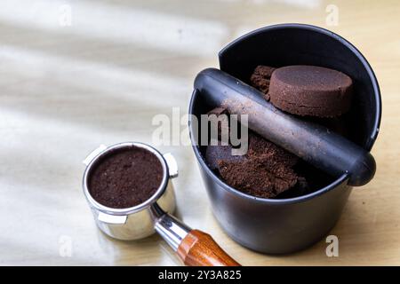 Caffè compattato macinato in scatola con portafiltro accanto. I fondi di caffè sono eccellenti fertilizzanti naturali e organici. Foto Stock