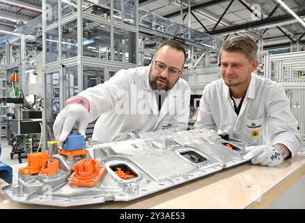 AMT Wachsenburg, Germania. 13 settembre 2024. Nino Sänn (l), dipendente della produzione, e Kay Hoschke (r), supervisore del turno, lavorano a un sistema di gestione delle batterie per il cliente Porsche il giorno dell'inaugurazione ufficiale di un nuovo locale di produzione presso Marquardt Systronics GmbH. Il fornitore automobilistico produce sistemi di gestione delle batterie in Turingia. Crediti: Martin Schutt/dpa/Alamy Live News Foto Stock