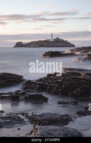 Una parte della costa della Cornovaglia con la bassa marea con il faro di Godrey sullo sfondo. Foto Stock