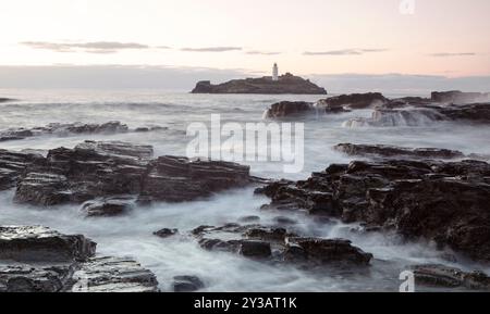 Una parte della costa della Cornovaglia con la bassa marea con il faro di Godrey sullo sfondo. Foto Stock