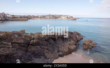Una costa rocciosa della cornovaglia con la città di St Ives sullo sfondo. Foto Stock