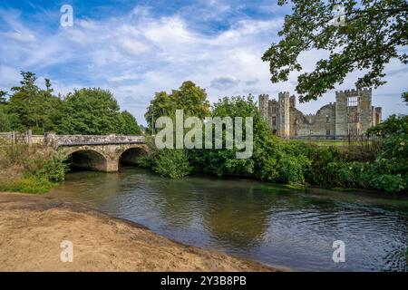 Un antico ponte di pietra sul fiume Rother che conduce all'ingresso delle rovine della Cowdray House a Midhurst, West Sussex, Inghilterra, Regno Unito. Foto Stock