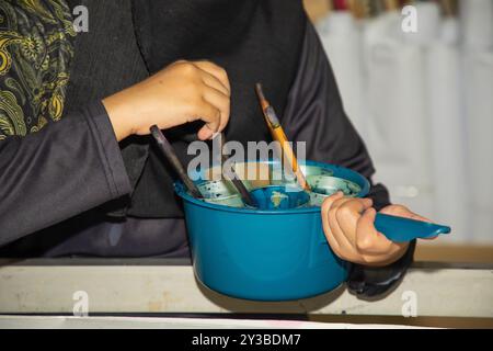 Disposizione artistica attrezzature e strumenti di batik malesi a mano con mani mans. paraffina per vernici speciali e pennelli. il posto di lavoro dell'artista in un batik fac Foto Stock