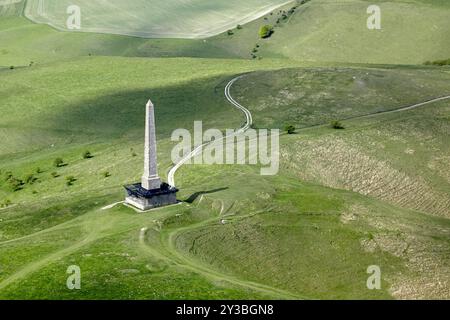 Fotografia aerea che cattura un obelisco solitario circondato da colline verdi e vivaci e da un percorso tortuoso nella campagna. Foto Stock