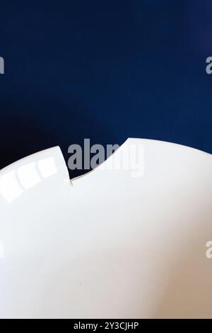 Piatto di zuppa di ceramica bianca rotto o scheggiato su sfondo blu scuro, vista dall'alto, nessuno Foto Stock