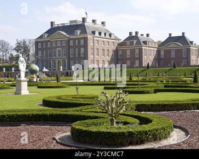 Un castello barocco con un giardino ben tenuto, siepi in bosso e diverse statue, sotto un cielo azzurro e limpido, Apeldoorn, Paesi Bassi Foto Stock