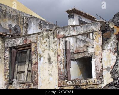 Primo piano delle finestre di una casa senza tetto abbandonata in rovina con tetti rotti e cielo grigio Foto Stock