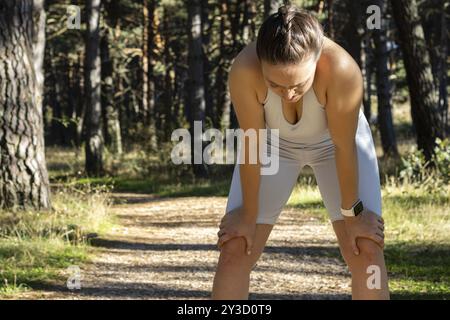 Ritratto frontale di una giovane donna con un look stanco appoggiata sulle ginocchia dopo l'esercizio fisico Foto Stock