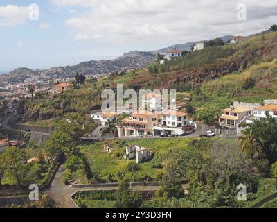 Una vista aerea di funchal a madeira con case e fattorie su una montagna con la città e la costa in lontananza Foto Stock