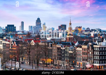 Amsterdam, Paesi Bassi, storico paesaggio urbano sul tetto con il moderno quartiere Zuidas in lontananza al crepuscolo. Foto Stock