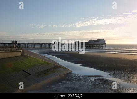 Vista del molo sud di blackpool al tramonto con la passeggiata e la spiaggia illuminata dalla luce del sole serale Foto Stock