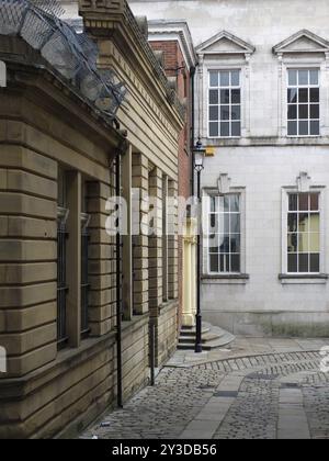 Vecchi edifici su una strada acciottolata nel centro di rochdale che guardano in discesa su un angolo affilato Foto Stock