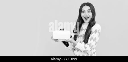 ragazza sorpresa tenere occhiali vr utilizzando la tecnologia futura per l'istruzione, scuola di realtà virtuale. Banner di bambina con visore VR per realtà virtuale, studio Foto Stock