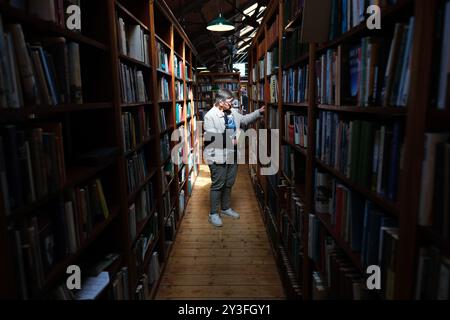 Hay on Wye, Powys, Wales UK un cliente che sfoglia i numerosi libri di seconda mano nella libreria Richard Booth nel settembre 2024 Foto Stock