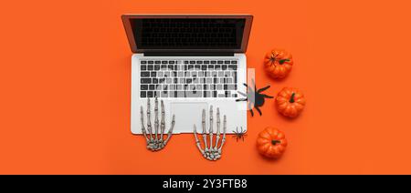 Laptop moderno e decorazioni per Halloween su sfondo arancione Foto Stock