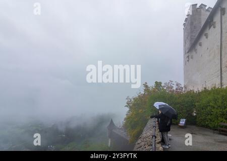 Salisburgo: Fortezza di Hohensalzburg, giorno di pioggia, turisti in abiti da pioggia e con ombrelloni, nebbia a Flachgau, Salisburgo, Austria Foto Stock