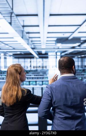 Team di tecnici del data center che monitorano il traffico e l'attività di rete, installando e configurando gli aggiornamenti software. Colleghi di lavoro di squadra che eseguono backup del database per proteggere le informazioni degli utenti Foto Stock