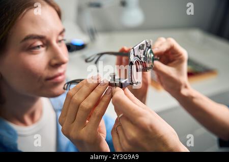 Paziente femmina che esamina le lenti nel telaio di prova Foto Stock