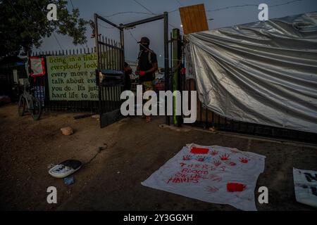 Sacramento, CA. 26 agosto 2024. Al mattino presto un manifestante con Camp Resolution riposa dopo aver stretto del filo spinato lungo il cancello e i residenti hanno messo dei cartelli dipinti intorno al perimetro dell'accampamento dei senzatetto autonomo in preparazione della città di Sacramento spazzata lunedì 26 agosto 2024. (Credit Image: © Renée C. Byer/ZUMA Press Wire) SOLO PER USO EDITORIALE! Non per USO commerciale! Foto Stock