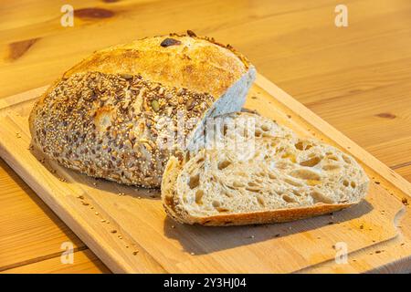 Pane fatto in casa e fette sul tavolo della cucina. Pane di segale con impasto naturale e vista ravvicinata dei semi Foto Stock