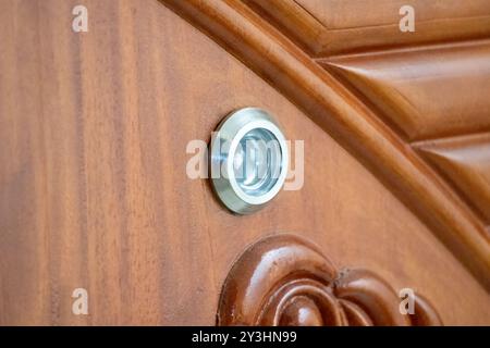 Vista ravvicinata dello spioncino nella porta di legno. È anche chiamato spioncino, spioncino, porta, occhio magico, specchio magico, spioncino. Foto Stock