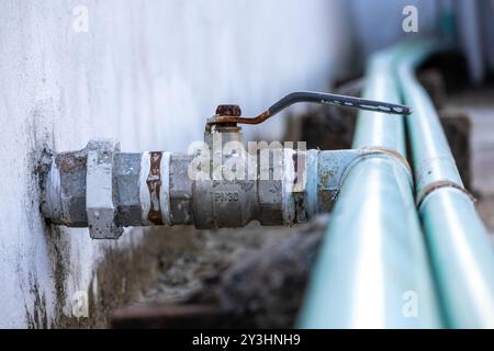 Primo piano del tubo idraulico e della valvola sul tetto dell'abitazione, sistema idrico contro la parete di cemento. Foto Stock