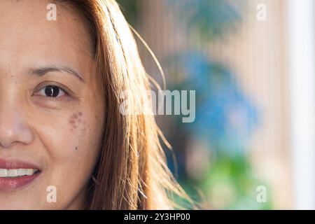 A casa, donna asiatica sorridente con capelli lunghi che guarda la macchina fotografica, primi piani, copia spazio Foto Stock