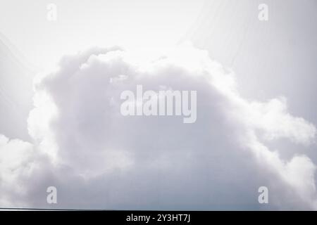 Goditi la serenità con questa immagine di serie che mostra delicate nuvole di cumulus che si muovono in un cielo blu sereno. La luce solare filtra tra tra le nuvole, producina Foto Stock