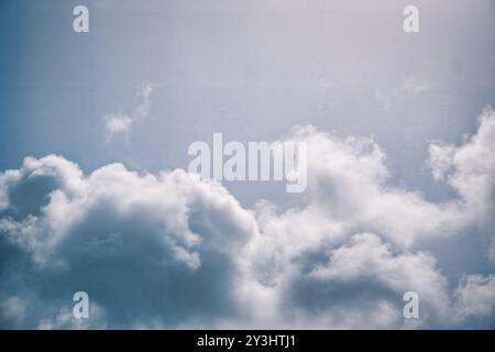 Cattura l'essenza della serenità con questa immagine stock caratterizzata da morbide nuvole di cumulus che fluttuano in un delicato cielo blu. La luce solare filtra attraverso il fl Foto Stock