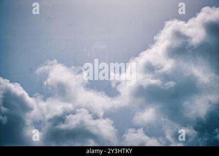 Cattura la tranquillità con questa immagine di serie caratterizzata da morbide nuvole di cumulus che fluttuano in un delicato cielo blu. La luce del sole si diffonde attraverso le nuvole, creat Foto Stock