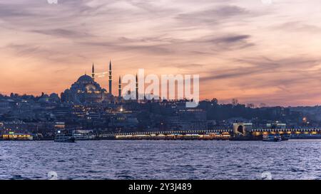 Splendida vista al tramonto dell'iconica Moschea di Suleymaniye con il vivace Corno d'Oro e il Ponte Galata in primo piano, che mostra la città Foto Stock