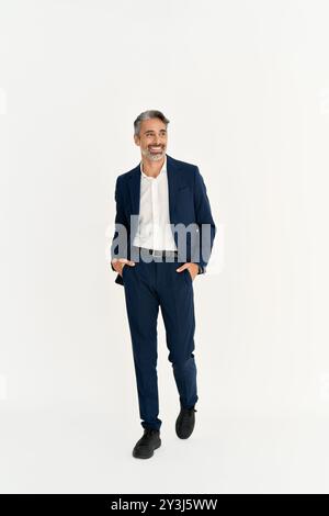 Felice uomo d'affari maturo in tuta che cammina isolato sul bianco. Corpo intero. Foto Stock