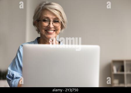 Una donna felice usa il laptop sorridente, leggendo buone notizie Foto Stock