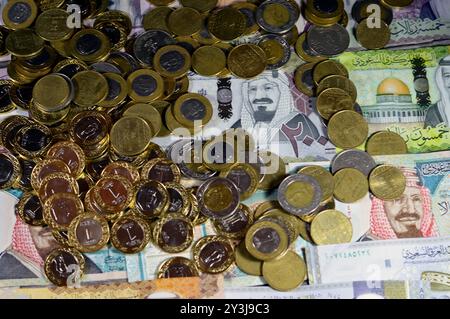 Monete di riyal saudita, 2, 1, mezza e un quarto di moneta su banconote in denaro saudita di riyal banconote, di diversi valori, moneta ed economia Foto Stock