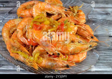 Mucchio di gamberi grigi non sbucciati cotti a vapore caldo e grigliati con fette di cipolla, cumino all'aglio, fette di peperoni colorati e sale cotto e g Foto Stock