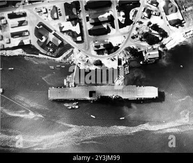 La portaerei USS Enterprise (CV-6) ormeggiata a Ford Island, Pearl Harbor, Hawaii, il 12 luglio 1942. Notate il Grumman F4F Wildcat sulla chiatta accanto, anche le reti anti-siluro e gli edifici mimetizzati sull'isola di Ford. Foto della Marina degli Stati Uniti. Foto Stock