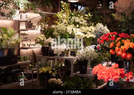 Elegante esposizione floreale bianca circondata da lussureggianti piante verdi e delicate fioriture in un elegante boutique di fiori al coperto Foto Stock