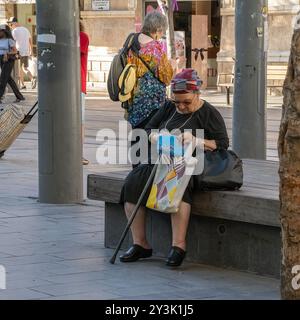 Gerusalemme, Israele - 18 luglio 2024: Una donna anziana seduta su una panchina nel centro di Gerusalemme, che guarda nella sua borsa. Foto Stock