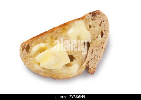 Un bicchierino di burro che si scioglie su fette di pane a lievitazione naturale tagliate su uno sfondo bianco: John Gollop Foto Stock