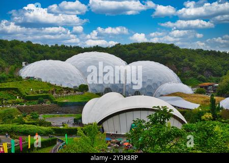 Una vista panoramica di futuristiche cupole geodetiche circondate da lussureggiante vegetazione sotto un cielo blu luminoso con soffici nuvole. Le cupole fanno parte di una g botanica Foto Stock