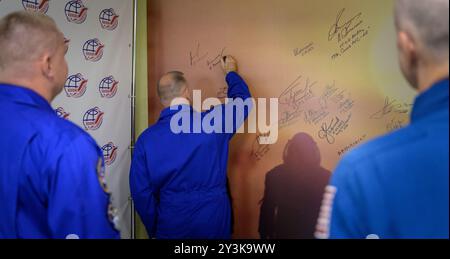 Baikonur, Kazakistan. 11 settembre 2024. Il cosmonauta di Roscosmos Ivan Vagner, centro, firma un murale presso il Cosmonaut Hotel prima di partire per vestirsi il giorno del lancio presso il cosmodromo di Baikonur, 11 settembre 2024, a Baikonur, Kazakistan. I membri dell'equipaggio della Expedition 72 si stanno dirigendo verso la stazione spaziale Internazionale per una rotazione di routine dell'equipaggio. Crediti: Bill Ingalls/NASA Photo/Alamy Live News Foto Stock