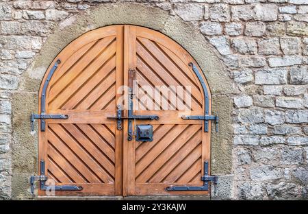 Antica porta di legno con metallo a cerniera e chiavistello, su un weathered muro di pietra Foto Stock